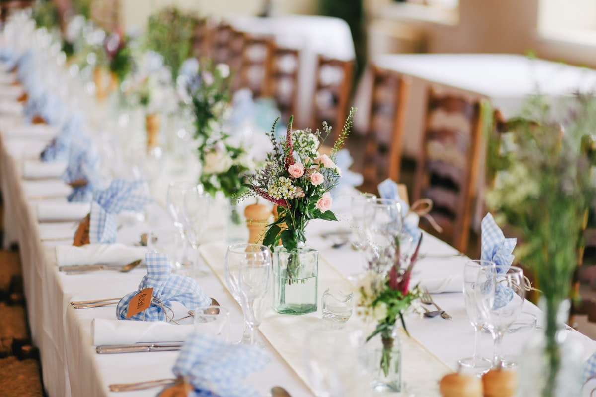 Longue table dressée avec fleurs et verrerie pour réception champêtre